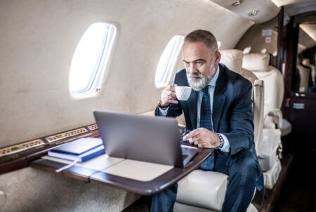 A passenger using a laptop in a business jet