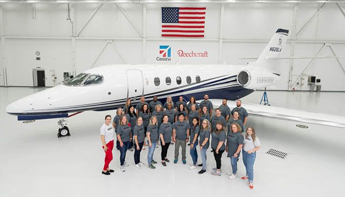 Group photo in front of business aircraft in hangar