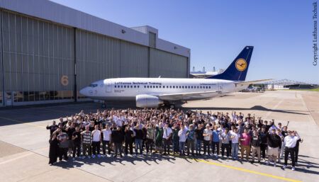 Group photo in front of aircraft outside hangar