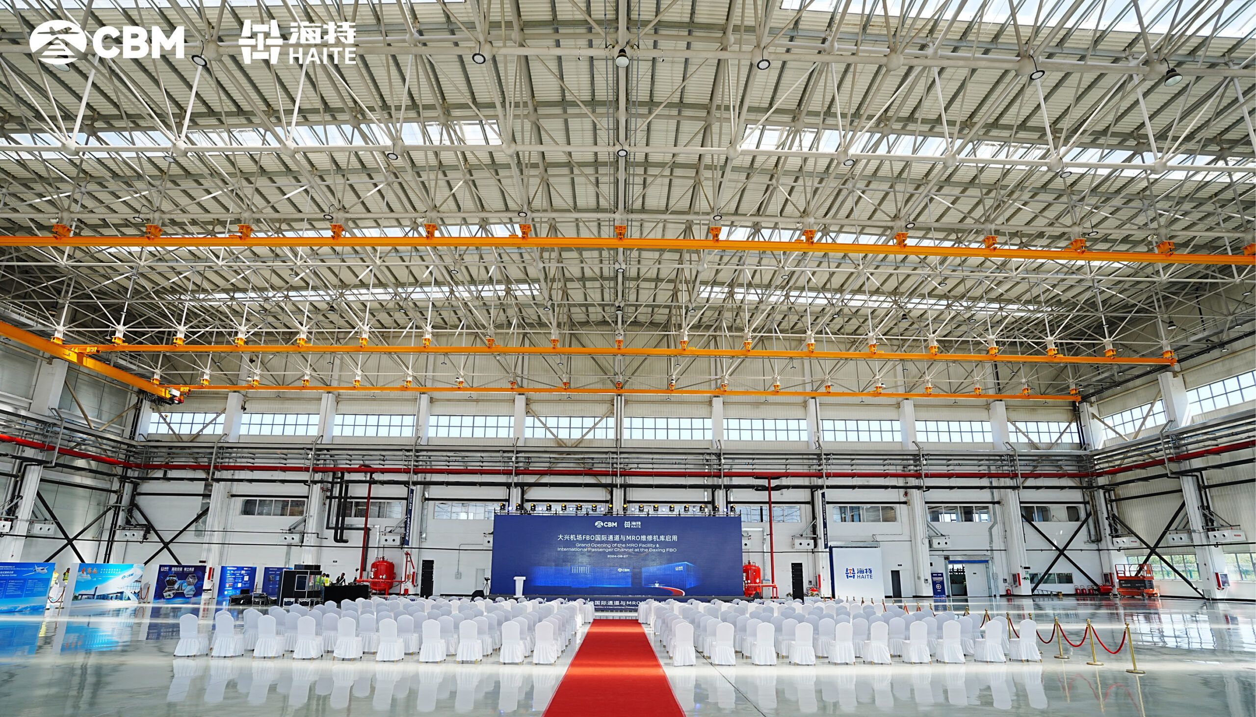 Hangar interior with rows of chairs facing a big screen