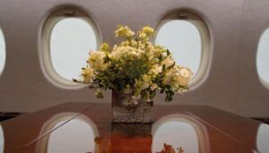 Table with bouquet of lowers in business jet, with windows in background