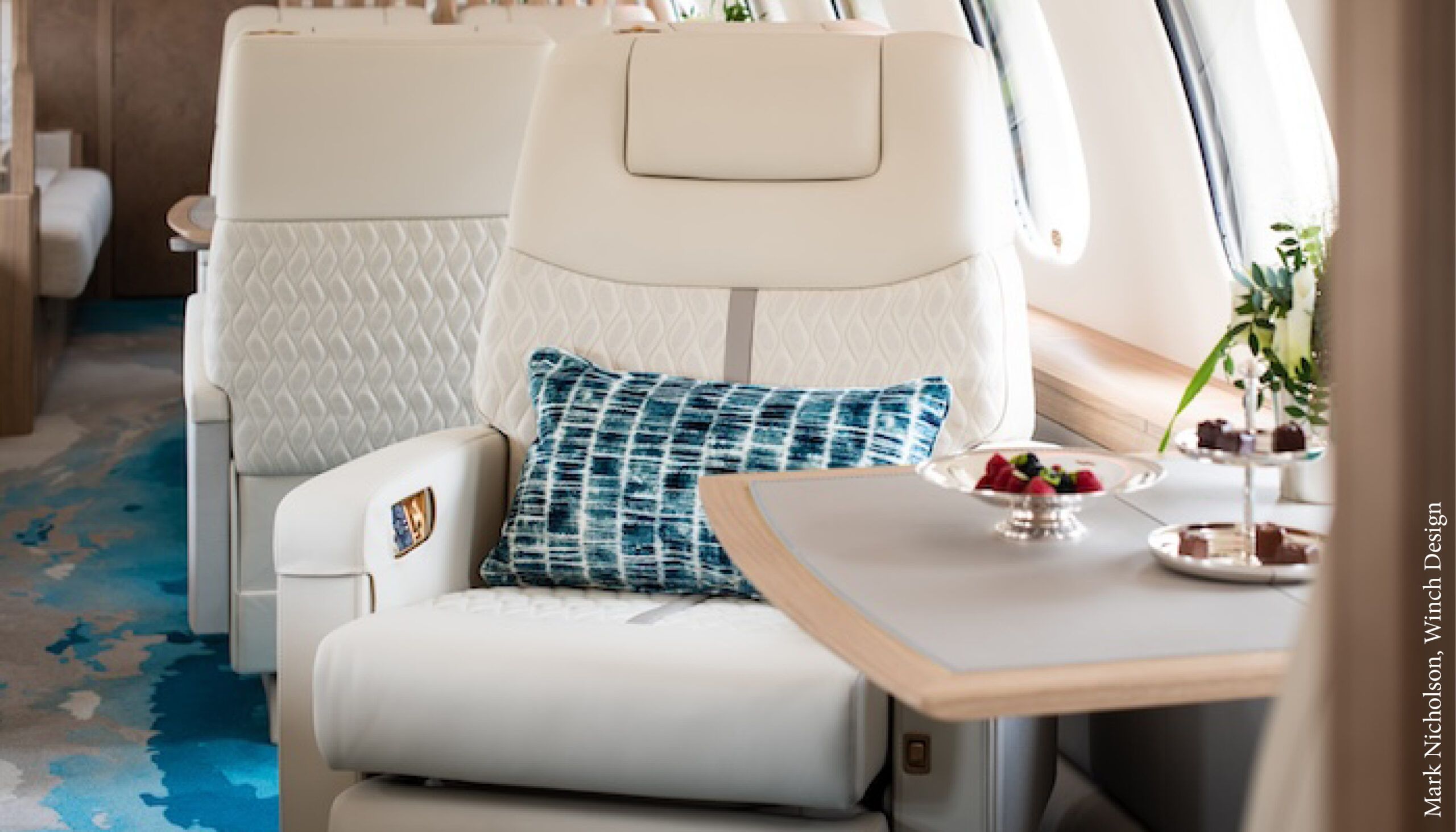 VIP aircraft seat in light-coloured leather with blue cushion and table in front