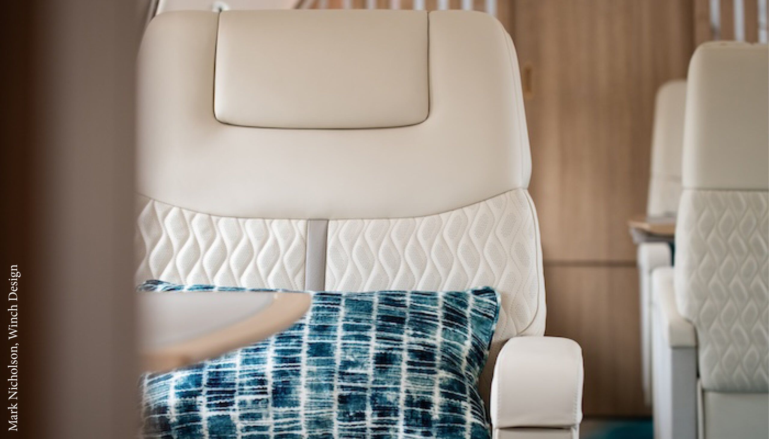 VIP aircraft seat in light-coloured upholstery with embossed section, and blue loose cushion