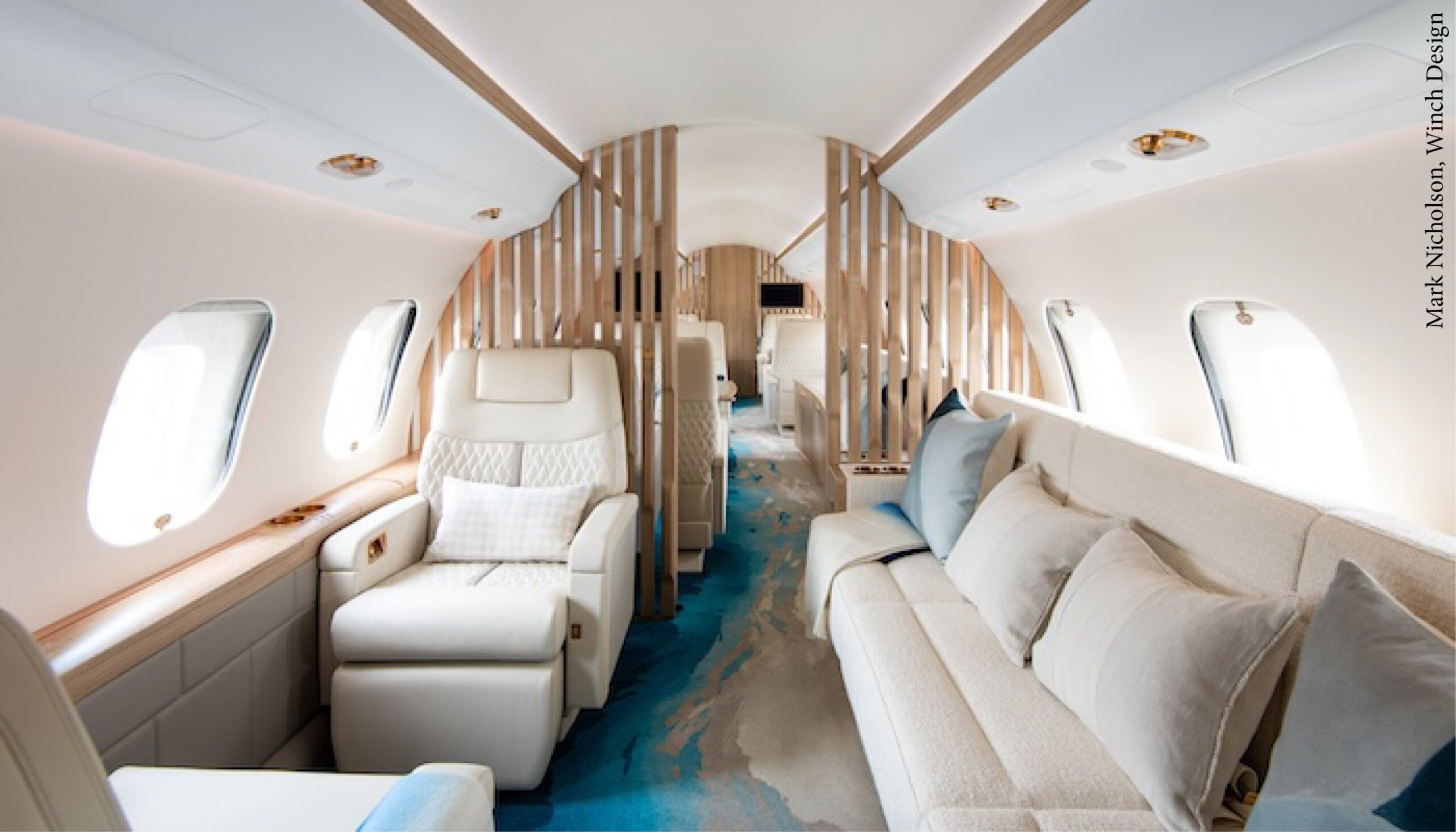 VIP aircraft interior with light-coloured seats and divan, and blue and cream carpet