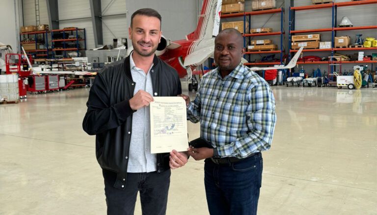 Two people holding certificate with aircraft and shelving in background