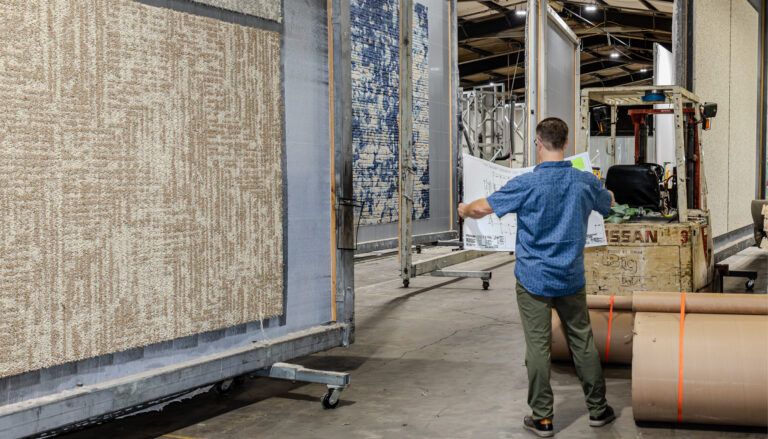 carpet manufacturing facility with large frames holding carpets and person in front