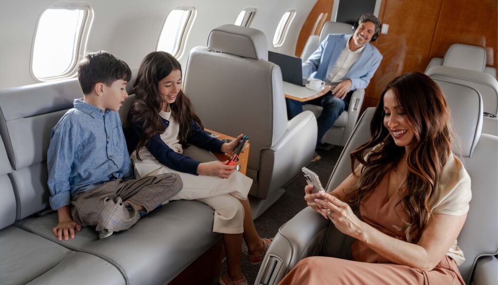 Family using phone, laptop and handheld videogame console on business jet