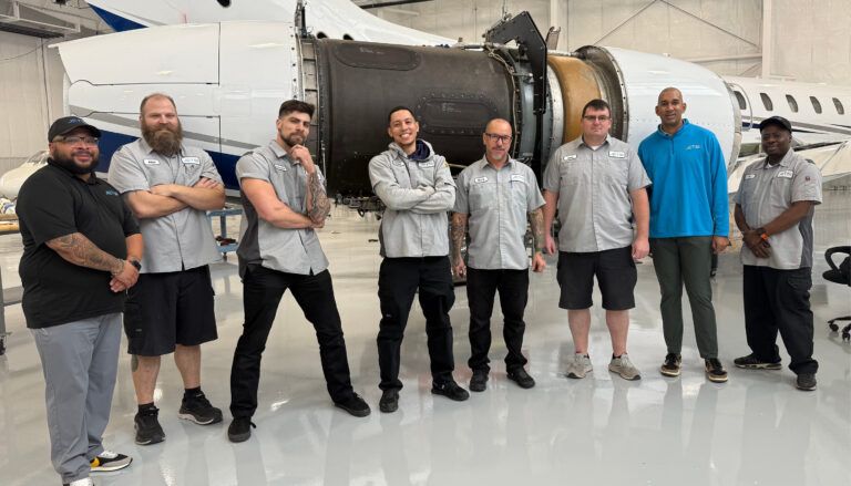 group photo in front of aircraft engine