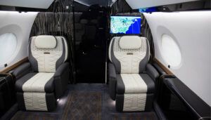 private jet interior with two seats in front of bulkhead with monitor