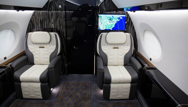 private jet interior with two seats in front of bulkhead with monitor