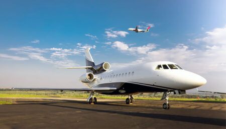 business jet at airport with another aircraft in flight