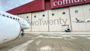 White business jet parked outside aircraft hangar with ‘TwoTwenty’ branding on building exterior