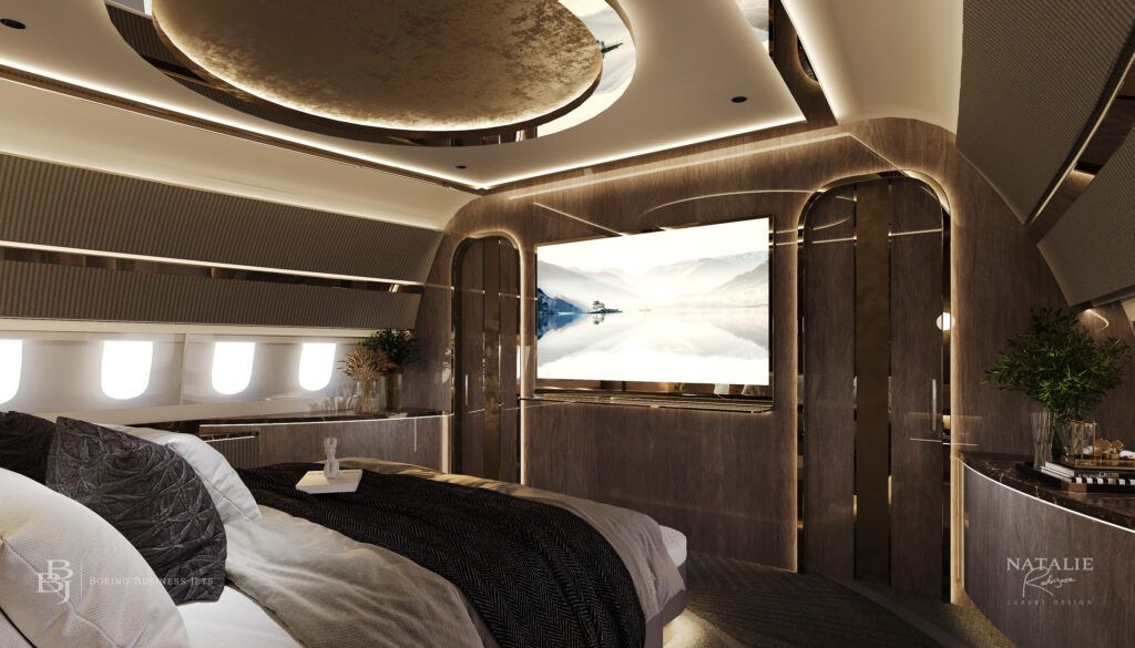 luxury aircraft bedroom featuring king-size bed with view to bulkhead screen, gold accents, overhead luminous circular feature