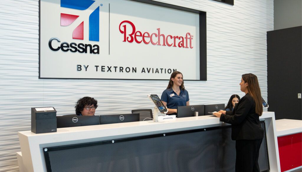 3 people behind reception desk, talking to one person on the other side of the desk