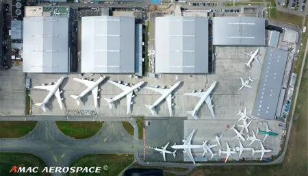 Bird's eye view of aircraft hangar complex with five B747-8i aircraft and other smaller types parked on the apron
