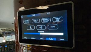 Aircraft cabin entertainment system display showing controls with HDMI, USB-C ports, Bluetooth options, volume slider, and navigation tabs.
