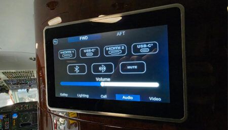 Aircraft cabin entertainment system display showing controls with HDMI, USB-C ports, Bluetooth options, volume slider, and navigation tabs.