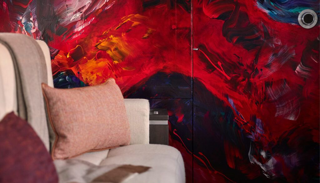 Private jet interior featuring dramatic red painted wall art and cream-coloured passenger seats.