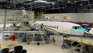 Business jet undergoing maintenance in hangar with scaffolding platforms
