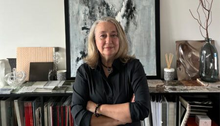Portrait of Agnès Guiu with material samples, files, and abstract artwork behind her