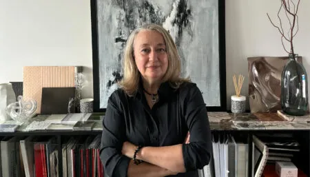 Portrait of Agnès Guiu with material samples, files, and abstract artwork behind her