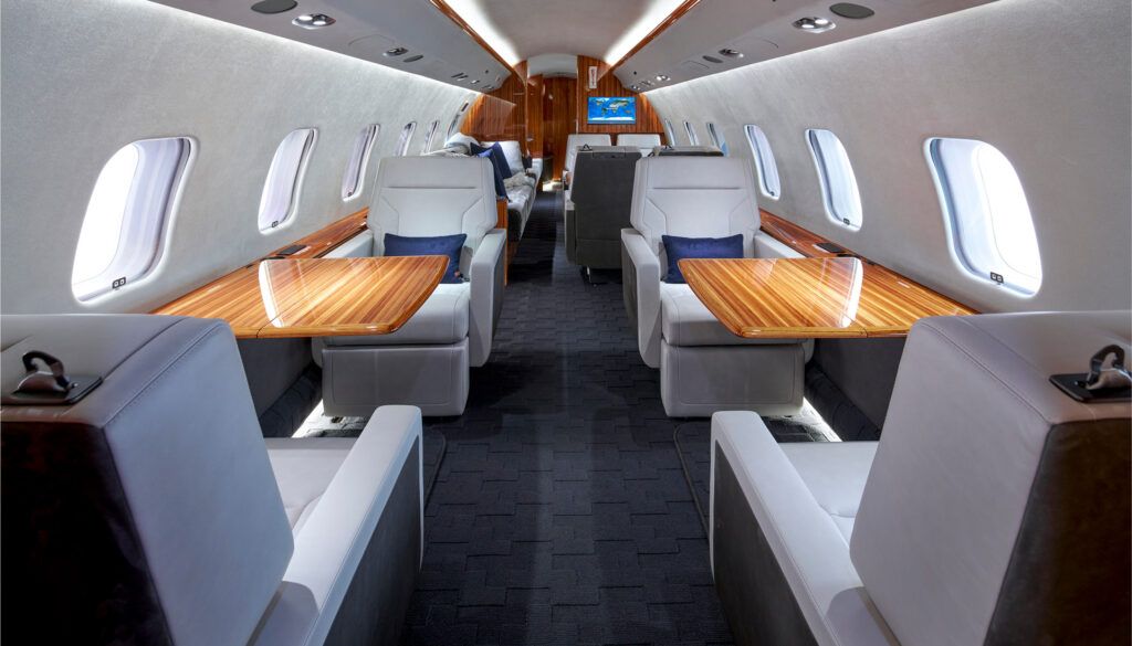 Luxurious private jet interior featuring white leather seats, wood tables, and modern cabin design