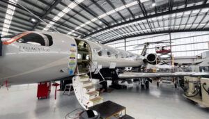 Embraer Legacy 500 aircraft in maintenance hangar with access stairs and equipment nearby