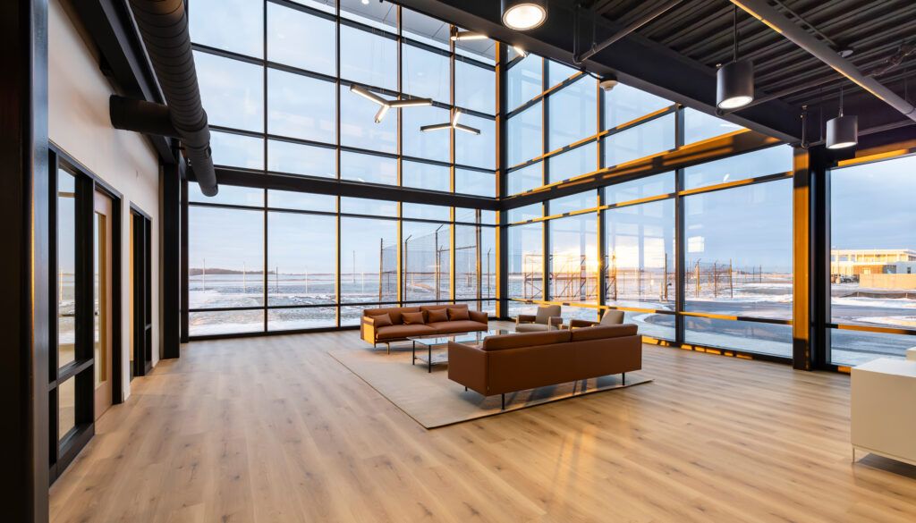 Modern airport lounge interior featuring floor-to-ceiling windows, leather furniture, and runway views