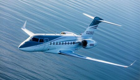 Gulfstream G280 aircraft in blue and white livery, flying over water