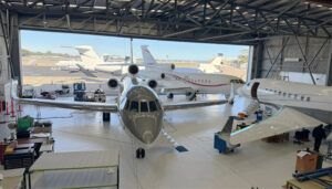 Business jets in hangar with maintenance crew working below