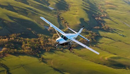 Cessna Citation Caravan flying over rolling green countryside
