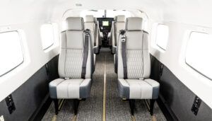 Aircraft cabin featuring light neutral leather seats with quilted inserts, cockpit in background