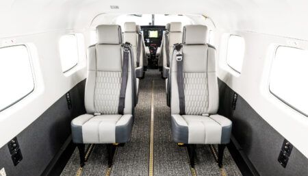 Aircraft cabin featuring light neutral leather seats with quilted inserts, cockpit in background