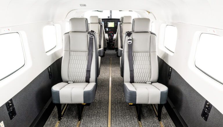 Aircraft cabin featuring light neutral leather seats with quilted inserts, cockpit in background