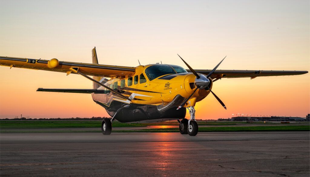 Turboprop aircraft with yellow, black and white paint scheme, on tarmac during sunset