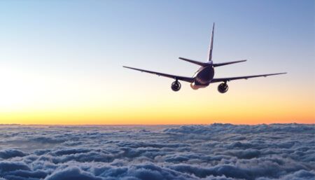 Aircraft flying over clouds at sunset