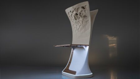 Mockup of sculptural cabin structure with complex, organic-looking decorative pattern of perforations and recesses, and attached table