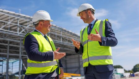 Peter Fortune MP and Sander Podgoric at construction site in hard hats and high-visibility vests