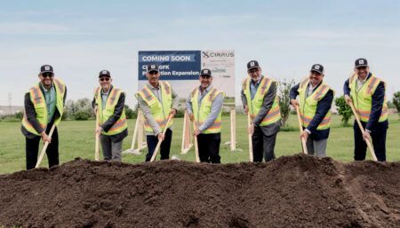 Seven executives in safety vests holding shovels at Cirrus groundbreaking ceremony