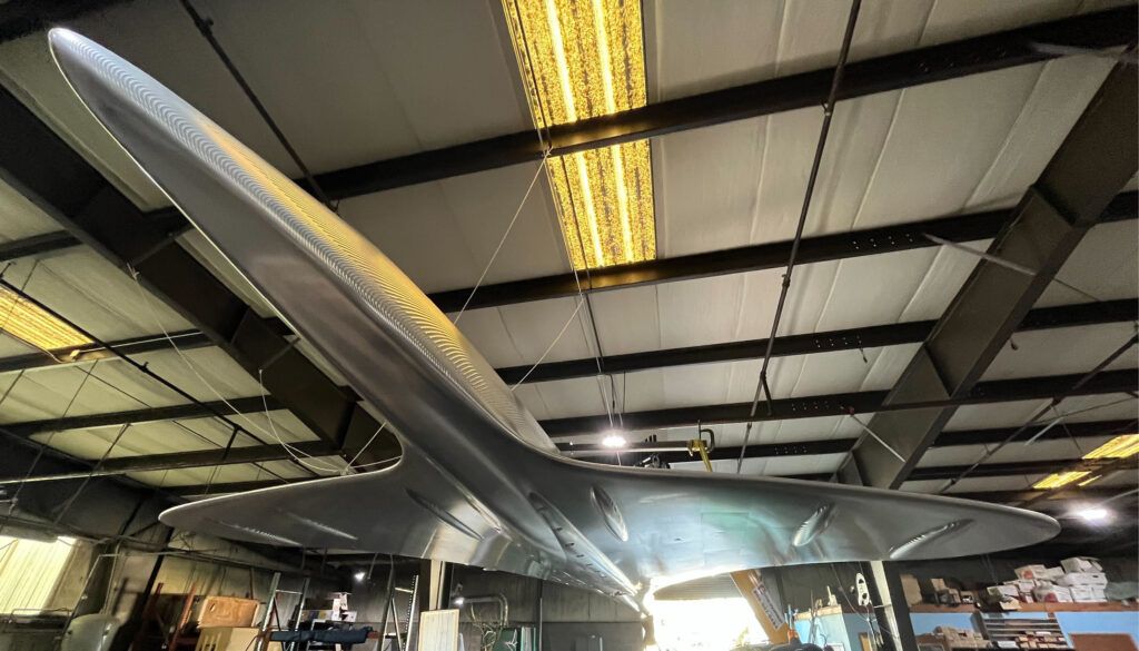 Large aluminium Concorde fuselage sculpture suspended from ceiling in workshop