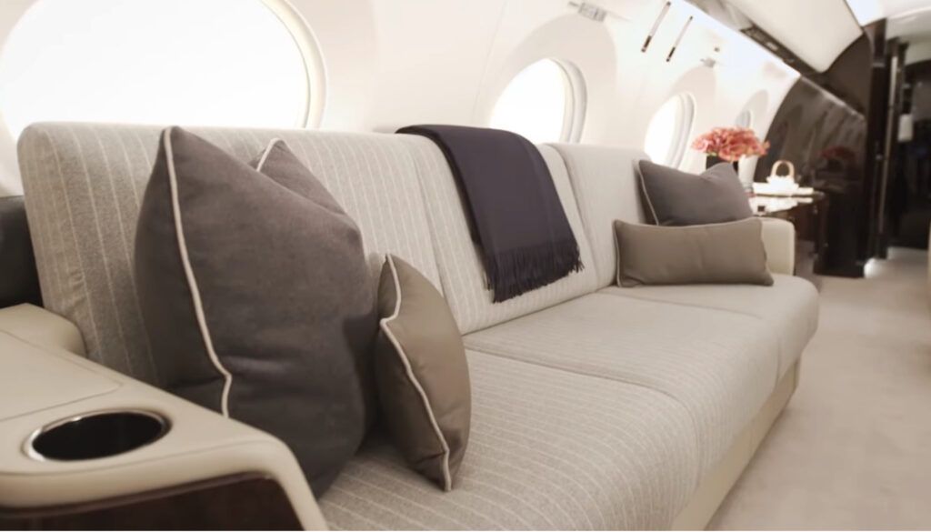 Luxurious private jet interior with divan in front of aircraft windows