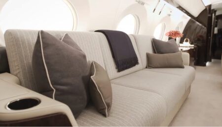 Luxurious private jet interior with divan in front of aircraft windows