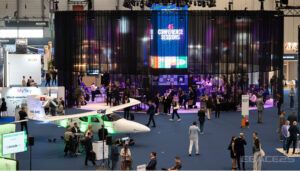 Tradeshow floor with aircraft displays and attendees networking under colourful lighting