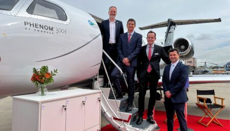 Four businessmen posing by Embraer Phenom 300E aircraft