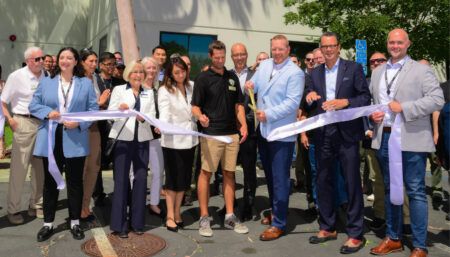 Group ribbon-cutting ceremony outside modern building with officials