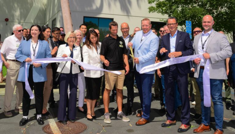 Group ribbon-cutting ceremony outside modern building with officials