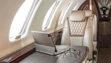 Business jet interior with cream leather seat at table with laptop