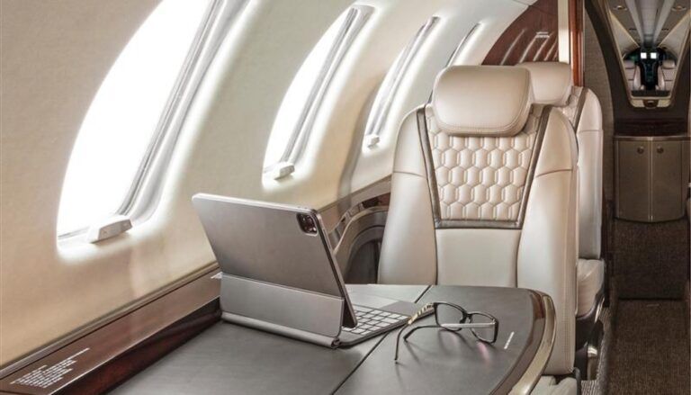 Business jet interior with cream leather seat at table with laptop