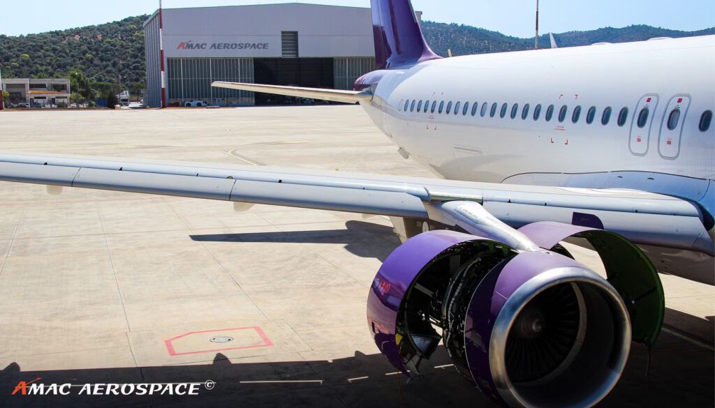 Aircraft with purple and white livery, outside AMAC Aerospace facility