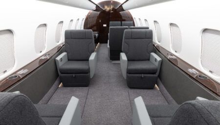 Private jet interior with grey seats and dark veneer